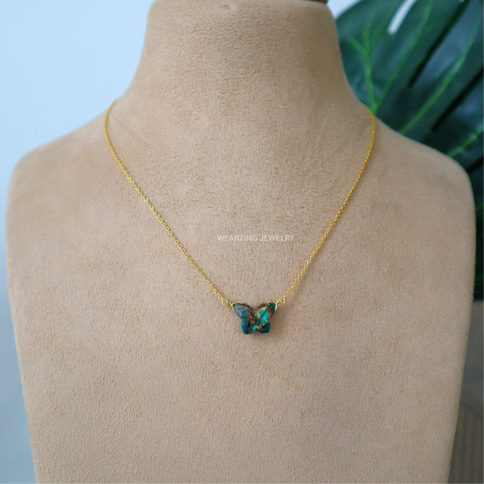 Gold necklace with a butterfly-shaped pendant on a mannequin bust.