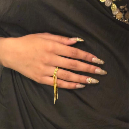 Hand with gold ring and nail polish wearing a black garment
