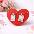 Two heart-shaped pendants on a red heart-shaped card with 'And Forever' text, surrounded by pink flowers.