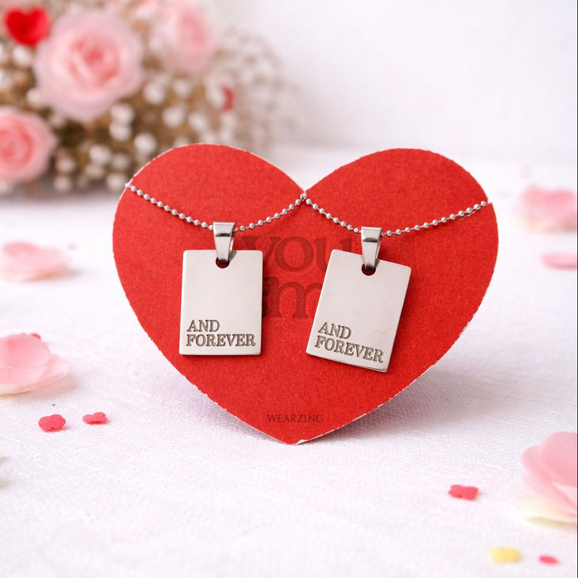 Two heart-shaped pendants on a red heart-shaped card with 'And Forever' text, surrounded by pink flowers.