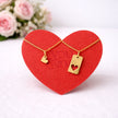 Red heart-shaped card with gold Couple necklace on a white background