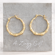 Gold hoop earrings on a gray card with text