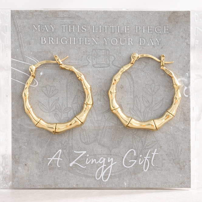 Gold hoop earrings on a gray card with text