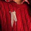 Red sweater with a silver brooch featuring dangling chains.