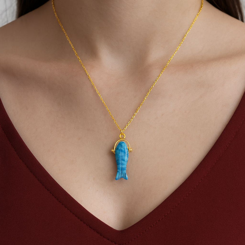 turquoise crystal pendant on a person wearing a red top.