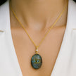 Gold necklace with an evil eye amulet pendant on a mannequin wearing a white blazer.