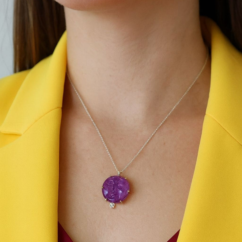 Purple pendant necklace on a person wearing a yellow blazer