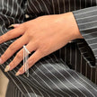 Person wearing a black pinstripe suit with jewelry, including rings and earrings.