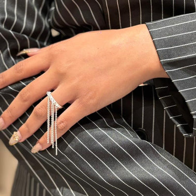 Person wearing a black pinstripe suit with jewelry, including rings and earrings.